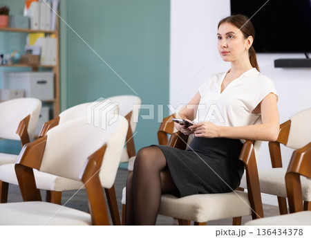 Young woman student listening to lecture with phone 136434378