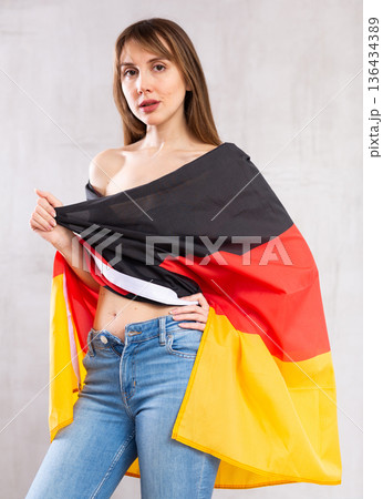 Attractive female football fan holding Germany flag 136434389
