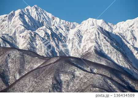 信州・長野の冬 冠雪した北アルプスの険しい稜線と青空の山岳風景 136434509
