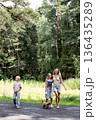 Happy family walking together with small dog on forest path. Smiling mother, son and daughter enjoying friendly atmosphere, togetherness, trust and warm outdoor in nature 136435289