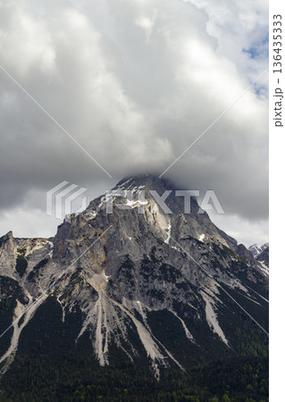 Close up vertical view of rocky Zugspitze summit hidden in heavy white clouds and fog. 136435333