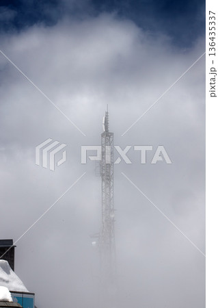 Telecommunication tower on Zugspitze peak surrounded by thick white clouds and fog. Minimalist view. Telecommunication tower on Zugspitze peak surrounded by thick white clouds and fog. Minimalist view. 136435337