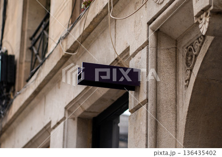 Blank dark blue sign projecting from an old stone building facade, symbolizing business opportunity, advertising, and urban retail space 136435402