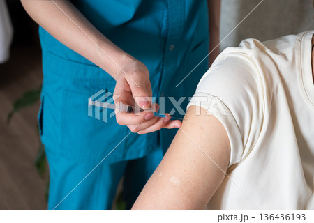 Nurse administers vaccine to patient in healthcare setting during daytime Nurse administers vaccine to patient in healthcare setting during daytime 136436193
