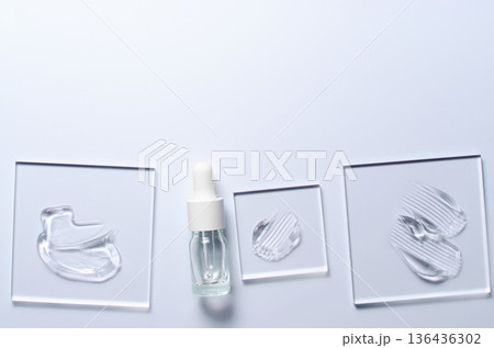 A sample of a transparent cosmetic skin care product on glass. Blue background 136436302