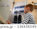 Young boy looking into open refrigerator at home, everyday domestic lifestyle 136436549
