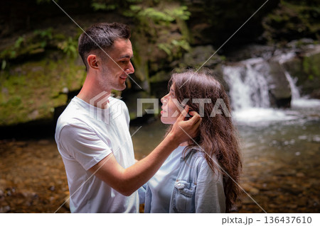 Young Couple Embracing Near Forest Waterfall 136437610