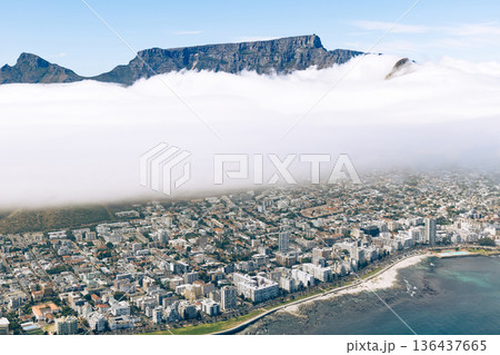 Aerial view of Cape Town city covered by fog with the top of Table mountain visible. South Africa travel and tourism concept. Aerial view of Cape Town city covered by fog with the top of Table mountain visible. South Africa travel and tourism concept. 136437665