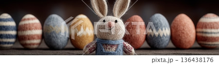 Knitted Easter bunny toy sitting among eggs greeting card. Knitted Easter bunny toy celebrating spring holiday with colorful background eggs 136438176
