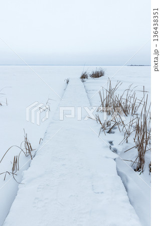 A serene winter scene features a snow-covered boardwalk 136438351