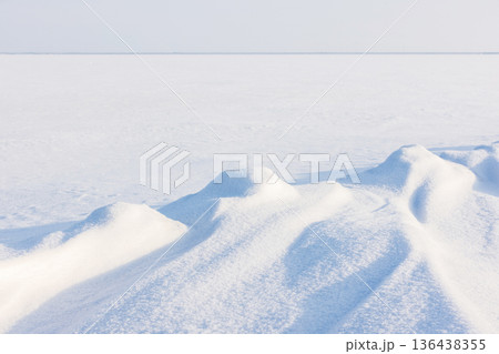 Snow dunes stretch across sunlit winter landscape 136438355