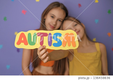 Cute, friendly, kind girls are hugging each other, showing the inscription autism on a postcard made of colorful paper letters. Autism Awareness Day Cute, friendly, kind girls are hugging each other, showing the inscription autism on a postcard made of colorful paper letters. Autism Awareness Day 136438636