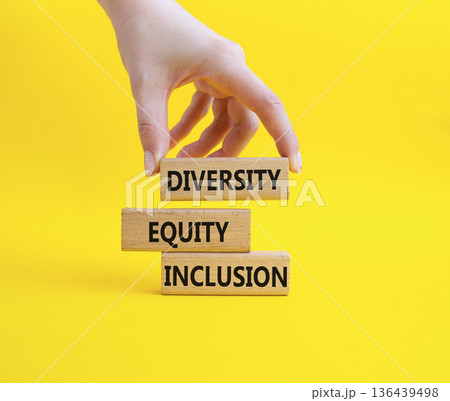 Diversity Equity Inclusion symbol. Concept words Diversity Equity Inclusion on wooden blocks. Businessman hand. Beautiful yellow background. Business and Diversity Equity Inclusion concept. Copy space 136439498