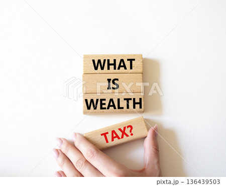 Tax symbol. Concept words What is Wealth Tax on wooden blocks. Beautiful bright white background. Businessman hand. Business and What is Wealth Tax concept. Copy space. Tax symbol. Concept words What is Wealth Tax on wooden blocks. Beautiful bright white background. Businessman hand. Business and What is Wealth Tax concept. Copy space. 136439503