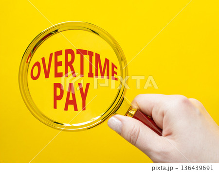 Overtime Pay symbol. Magnifying Glass with words Overtime Pay. Businessman hand. Beautiful yellow background. Business and Overtime Pay concept. Copy space. Overtime Pay symbol. Magnifying Glass with words Overtime Pay. Businessman hand. Beautiful yellow background. Business and Overtime Pay concept. Copy space. 136439691