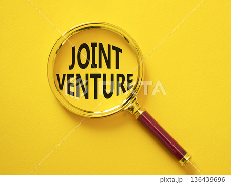 Joint Venture symbol. Magnifying Glass with words Joint Venture. Beautiful yellow background. Business and Joint Venture concept. Copy space. 136439696