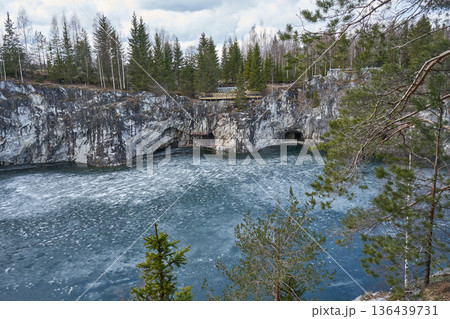 Winter landscape of Ruskeala Mountain Park with frozen lake. Marble canyon and surrounding forest in nature reserve. Outdoor travel. Winter landscape of Ruskeala Mountain Park with frozen lake. Marble canyon and surrounding forest in nature reserve. Outdoor travel. 136439731