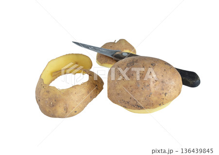 A potato and a potato peel lie next to a knife. A potato and a potato peel lie next to a knife. 136439845