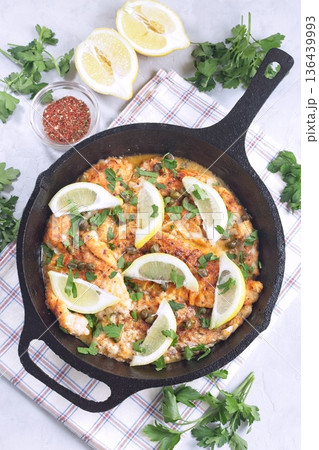 Delicious haddock fish piccata with lemon and capers in cast iron pan, vertical, top view 136439993