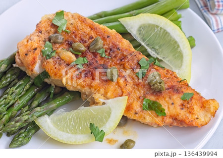 Delicious haddock fish piccata, battered fish fillet with capers, lemon and asparagus, horizontal Delicious haddock fish piccata, battered fish fillet with capers, lemon and asparagus, horizontal 136439994