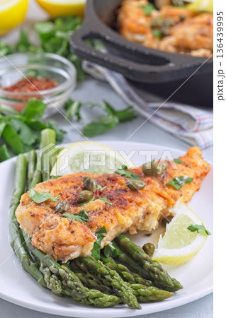 Delicious haddock fish piccata, battered fish fillet with capers, lemon and asparagus, vertical Delicious haddock fish piccata, battered fish fillet with capers, lemon and asparagus, vertical 136439995