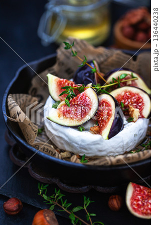 Camembert or brie cheese with fresh figs walnuts and honey on iron frying pan, over dark background Camembert or brie cheese with fresh figs walnuts and honey on iron frying pan, over dark background 136440238