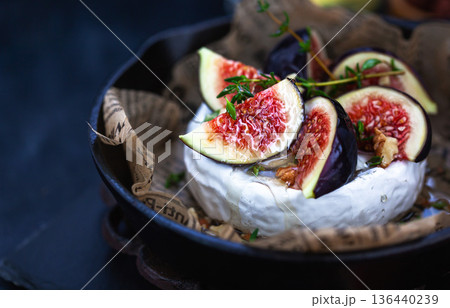 Camembert or brie cheese with fresh figs walnuts and honey on iron frying pan, over dark background Camembert or brie cheese with fresh figs walnuts and honey on iron frying pan, over dark background 136440239