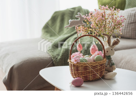 Easter Basket with Ester Eggs,  Plush Bunny and Spring Decor on White Table intoCozy Living Room 136442656