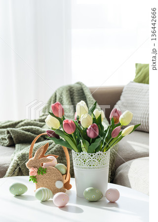 Easter Bunny Basket with Decorated Eggs and Tulip Bouquet. Cozy Spring Arrangement Easter Bunny Basket with Decorated Eggs and Tulip Bouquet. Cozy Spring Arrangement 136442666