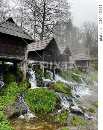 Traditional wooden water mills in Jajce, Bosnia, surrounded by flowing streams and mossy rocks, creating a scenic rural landscape with heritage and nature harmony 136443191