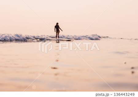 Woman on longboard riding on small wave with warm sunrise . Woman on longboard riding on small wave with warm sunrise . 136443249