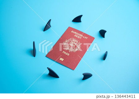 The Estonian passport is surrounded by a circle of shark fins. Legal, financial, and tax obligations that create challenges for expatriates. Immigration law, citizenship analysis, and global mobility 136443411