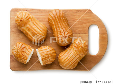 Eclairs and halves on a wooden board on a white background. Top view Eclairs and halves on a wooden board on a white background. Top view 136443481