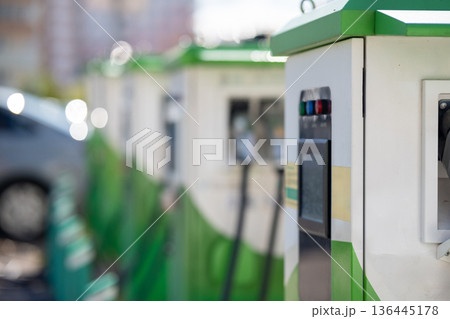 Close-up of an electric vehicle charging station with indicator lights and display. Close-up of an electric vehicle charging station with indicator lights and display. 136445178