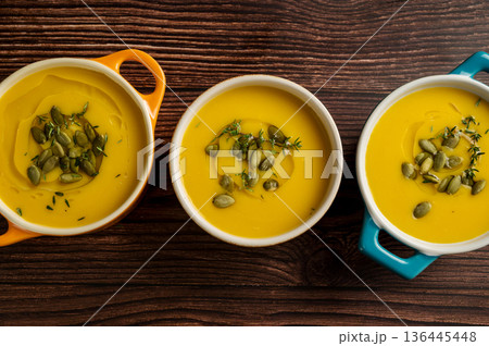 Pumpkin soup in ceramic bowls, wooden background, top view 136445448