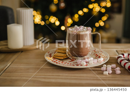 Holiday, Christmas background. A cup with hot chocolate and marshmallows on the table with Christmas tree on background 136445450