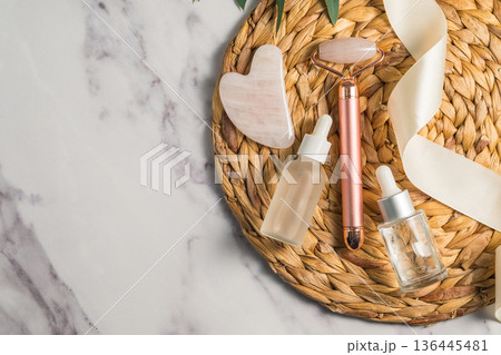 Rose quartz gua sha tool and face massage roller on wooden tray, beauty abstract photo. Top view 136445481
