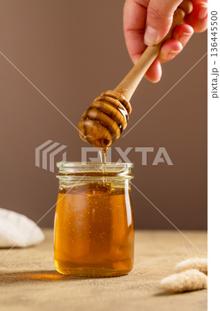 Jar of honey with wooden dipper, sweet liquid, neutral background Jar of honey with wooden dipper, sweet liquid, neutral background 136445500