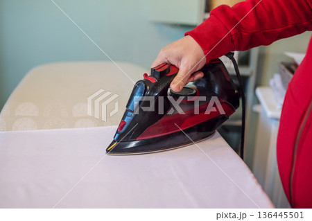 Man's hand ironing clothes on an ironing board at home Man's hand ironing clothes on an ironing board at home 136445501
