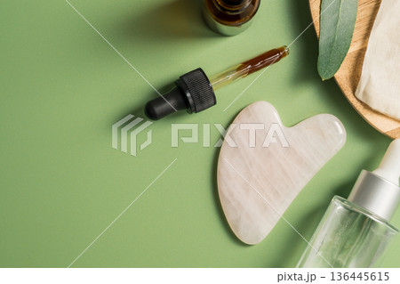 Rose quartz gua sha tool and oil bottle on wooden tray, face massage tool, beauty abstract photo. Copy space 136445615