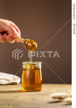 Jar of honey with wooden dipper, sweet liquid, neutral background 136445626
