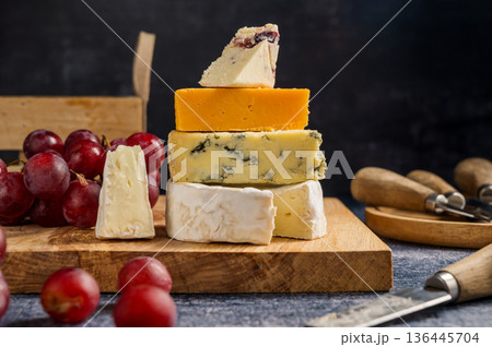 Different types of cheese on a board, served with grapes and dried fruits. 136445704
