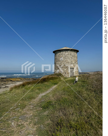 Stone coastal windmill on grassy cliff beside narrow footpath, Atlantic shoreline in Viana de Castelo along Camino de Santiago. Tourism promotion, cultural heritage storytelling, slow travel campaigns Stone coastal windmill on grassy cliff beside narrow footpath, Atlantic shoreline in Viana de Castelo along Camino de Santiago. Tourism promotion, cultural heritage storytelling, slow travel campaigns 136446087
