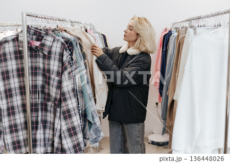 Young Caucasian Blonde Woman Standing between the Rails with Shirts and t-shirts Young Caucasian Blonde Woman Standing between the Rails with Shirts and t-shirts 136448026