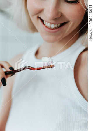 Close up view on toothbrush with toothpaste in smiling blonde woman hand 136448031
