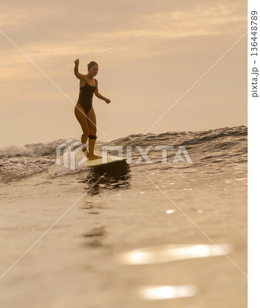 Sunset Glow Silhouettes Woman Skating On Longboard Over Water 136448789