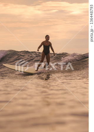 Sunset Glow Silhouettes Woman Skating On Longboard Over Water 136448793