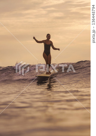 Sunset Surf Serenity, Peaceful Scene Of Lady Ending Her Surfing As Day Fades 136448794