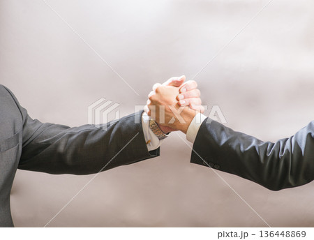 Two businessmen partner to greet each other, a firm handshake 136448869