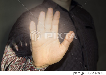 Businessman showing stop gesture on gray background, the palm is lit by sunlight Businessman showing stop gesture on gray background, the palm is lit by sunlight 136448898